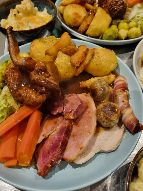A Sunday roast plate with gammon and pork, Yorkshire pudding, roast potatoes, pig in blanket, stuffing, carrots and cabbage